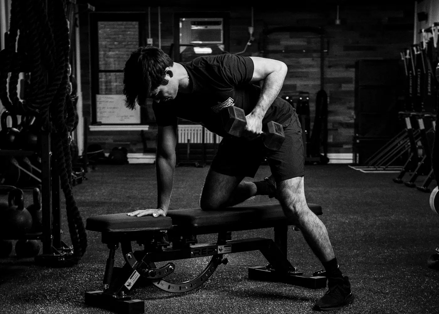 A lifter performing a single-arm dumbbell row on a bench